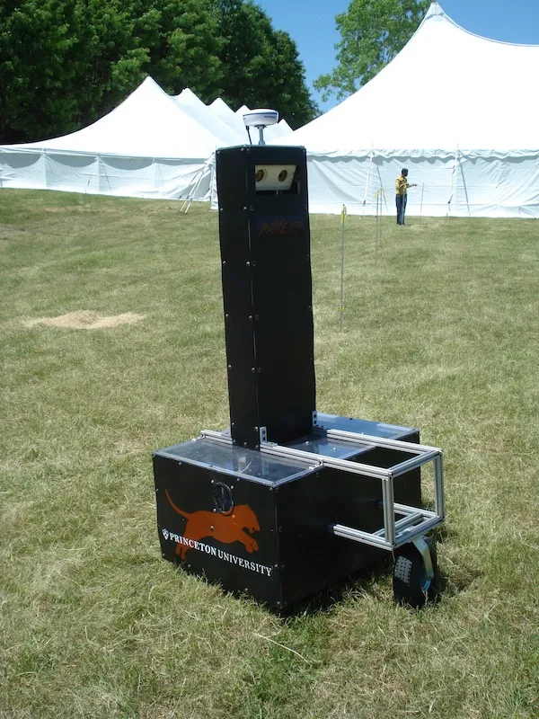 Argos, large, black robot with tall sensor system sits in grass