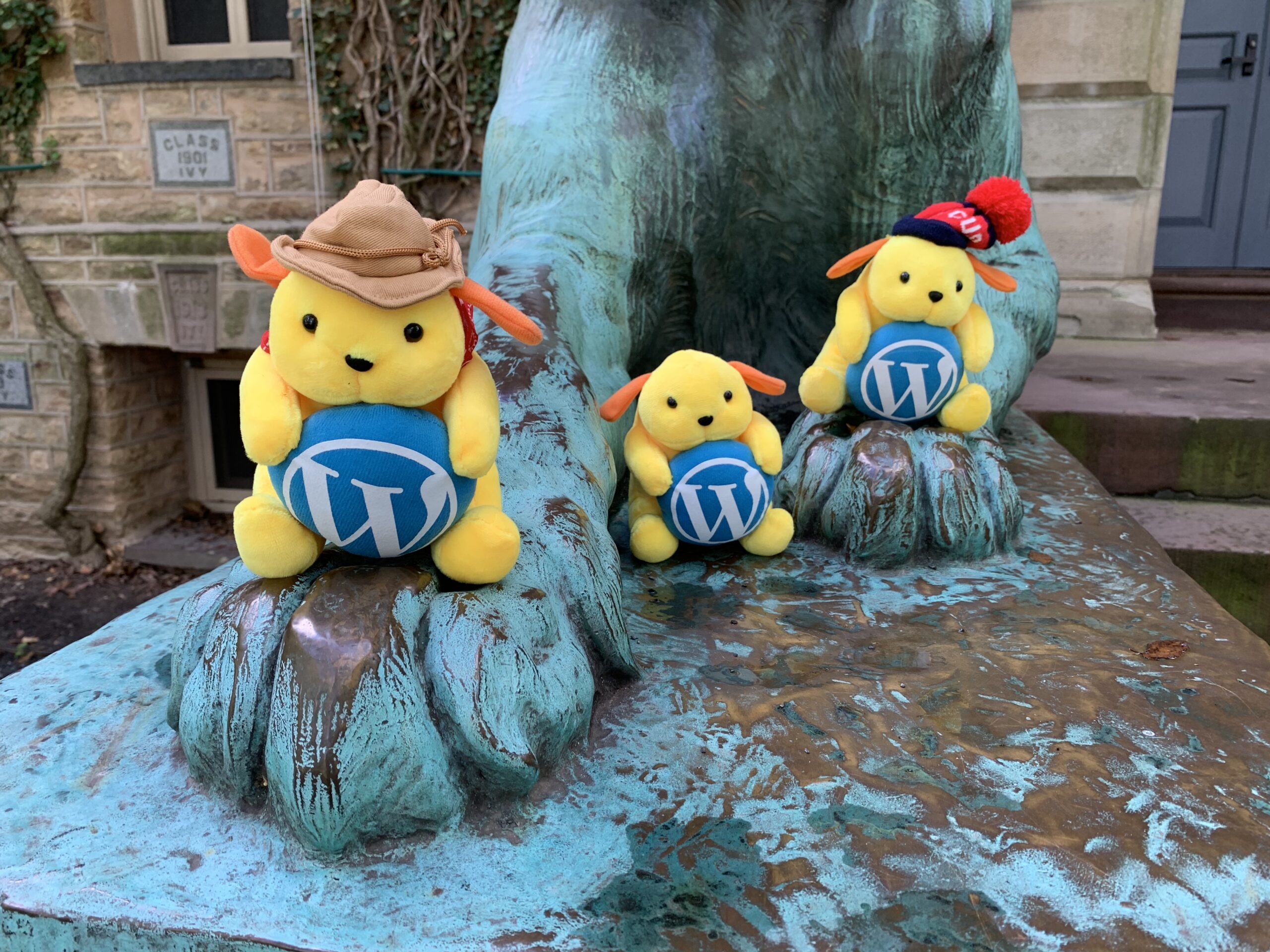 Stuffed WordPress mascots sitting on feet of Nassau Hall tiger