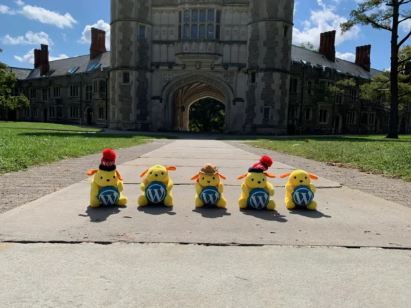 Five stuffed WordPress mascots in front of Blair Arch